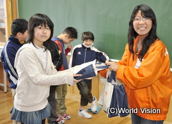 学用品を手渡す山野スタッフ（右）